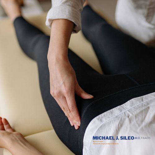 A person in black leggings receives a physical examination of the hip or thigh area by a healthcare professional, highlighting Common Signs You Might Have a Hip Labral Tear. Michael J. Sileo, M.D. logo is visible.