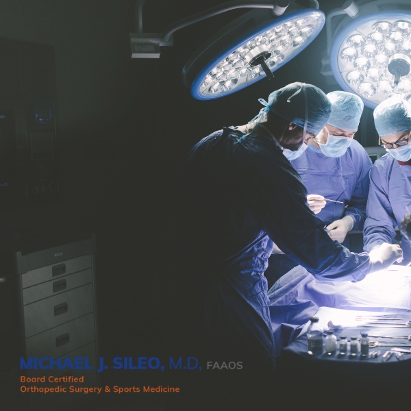 Commack Orthopedic Surgeons perform an operation in a brightly lit operating room, with surgical instruments neatly arranged on a nearby table. Commack Orthopedic Surgeons perform an operation in a brightly lit operating room, with surgical instruments neatly arranged on a nearby table